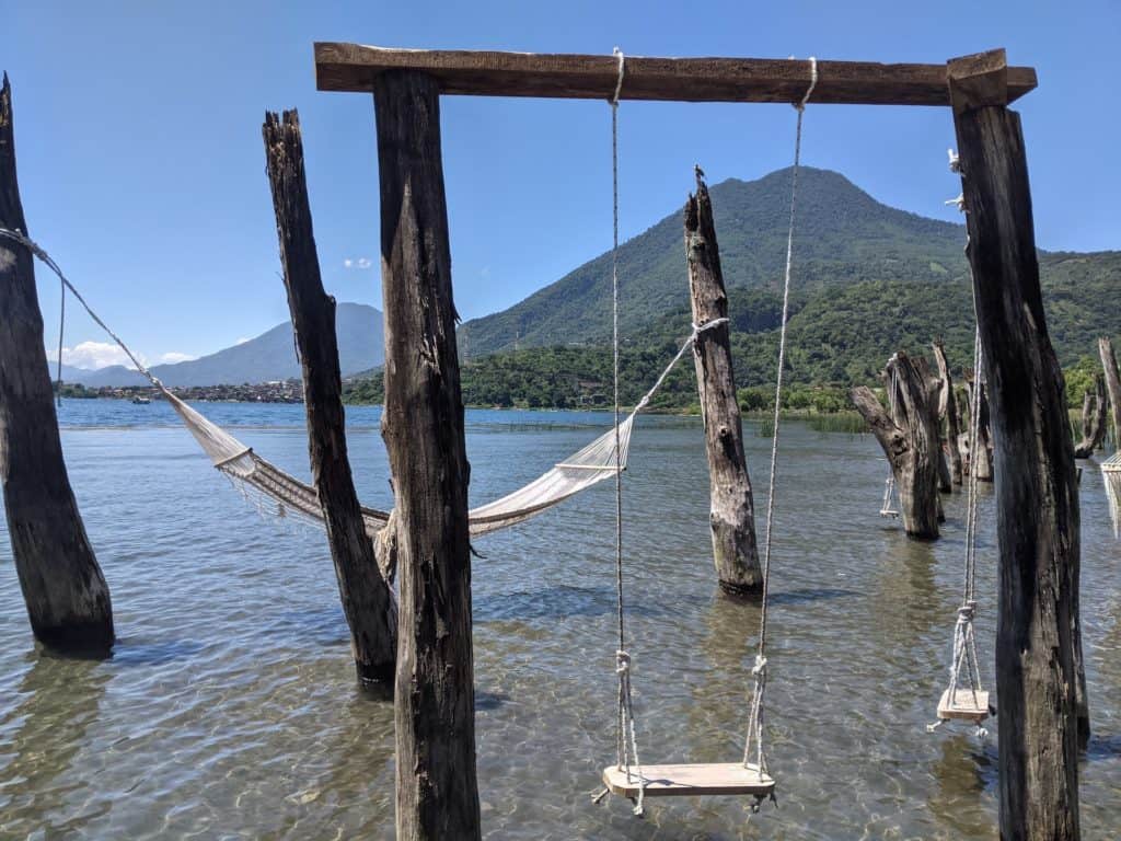 Hamacas y columpios sobre el agua en el lago de Atitlán con vistas de los volcanes al fondo