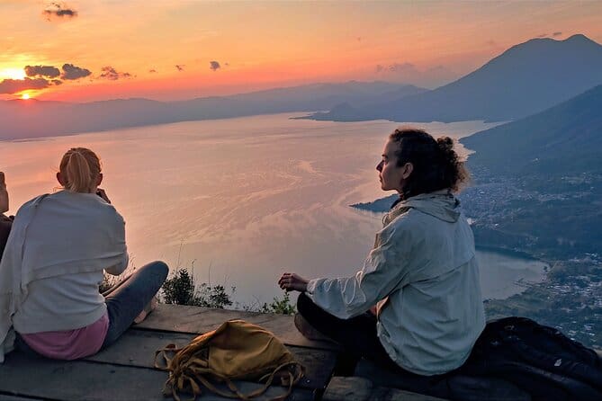 two tourists watch the sun rise over lake atitlan