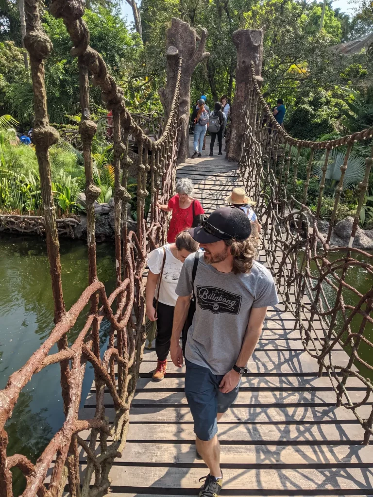 people walking across a suspension bridge at the guatemala zoo