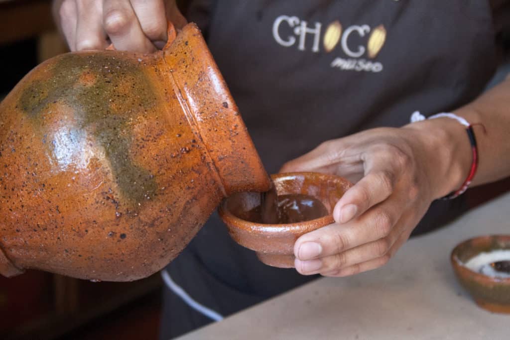 Guía de chocolate de Choco Museo vertiendo chocolate en una pequeña taza de arcilla