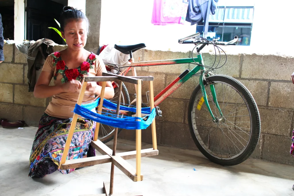 Young Mayan woman showing how to separate and prepare threads for weaving