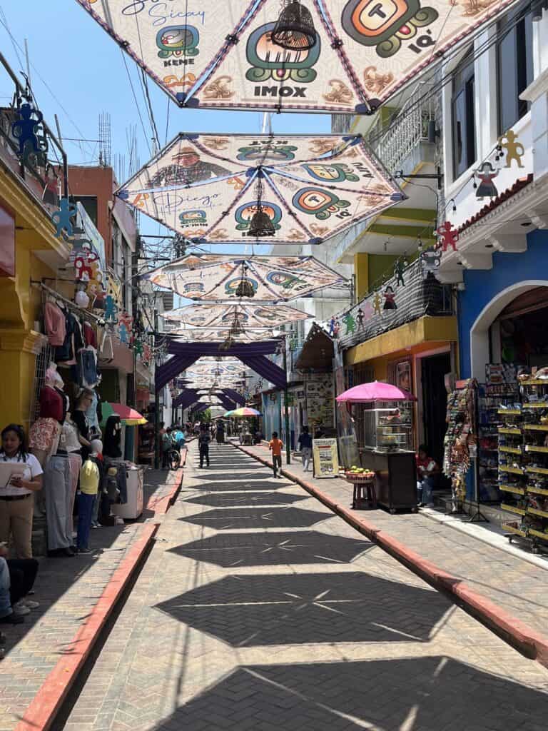 Decorated hexagons hang above a colorful street in San Juan la Laguna