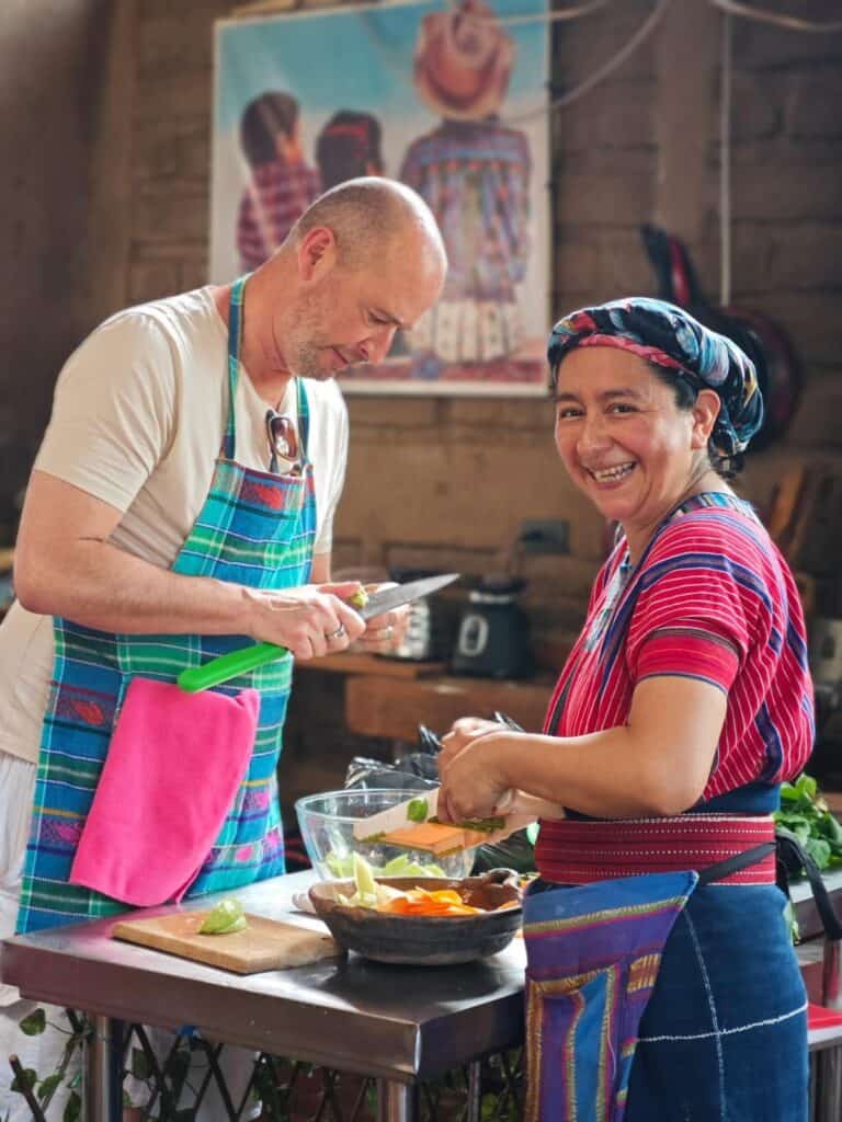 A Maya Tzutujil woman helps a foreign visitor prepare food during a cultural cooking class in San Juan la Laguna Guatemala.