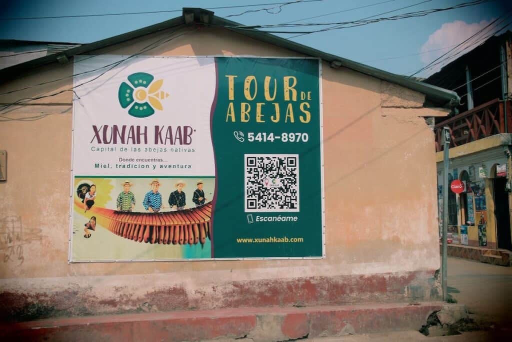 A sign advertising the stingless bee tour is draped on the side of a house