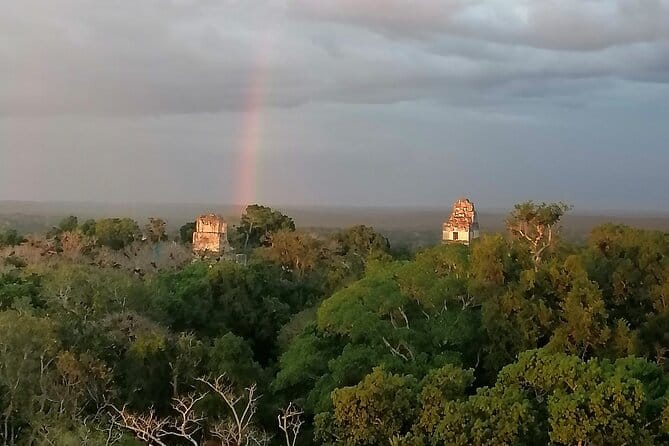 Rainbow beaming down on the ruins of Tikal peaking above the jungle canopy