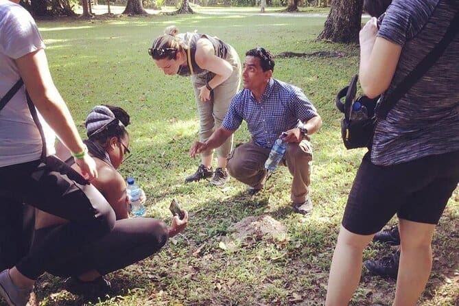 Tour guide at Tikal National Park crouching with tourists to discuss something. Guides are what make Tikal tours from Flores extra fun.